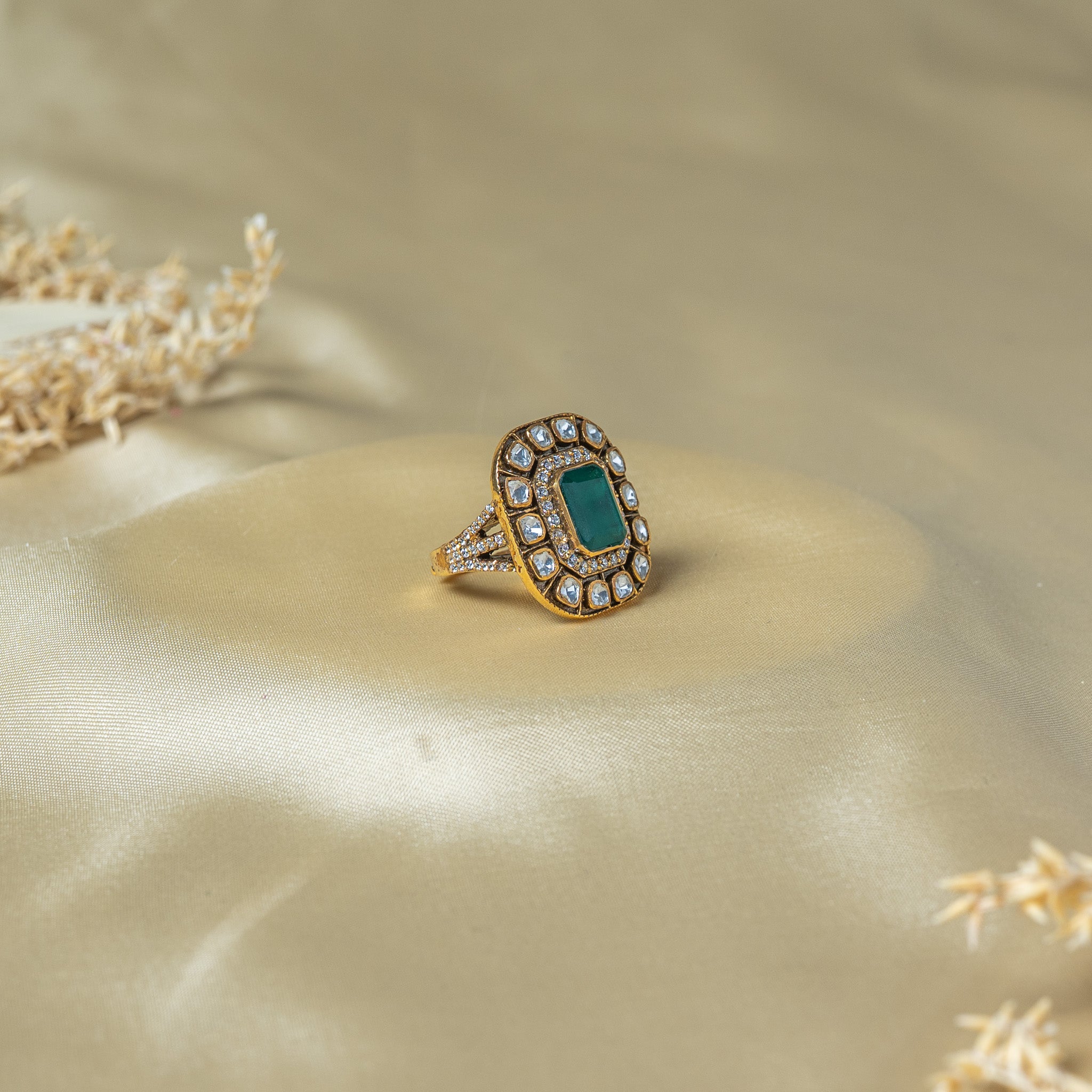 Angled view of the green centre stone and the pave set split band in gold plated 925 silver