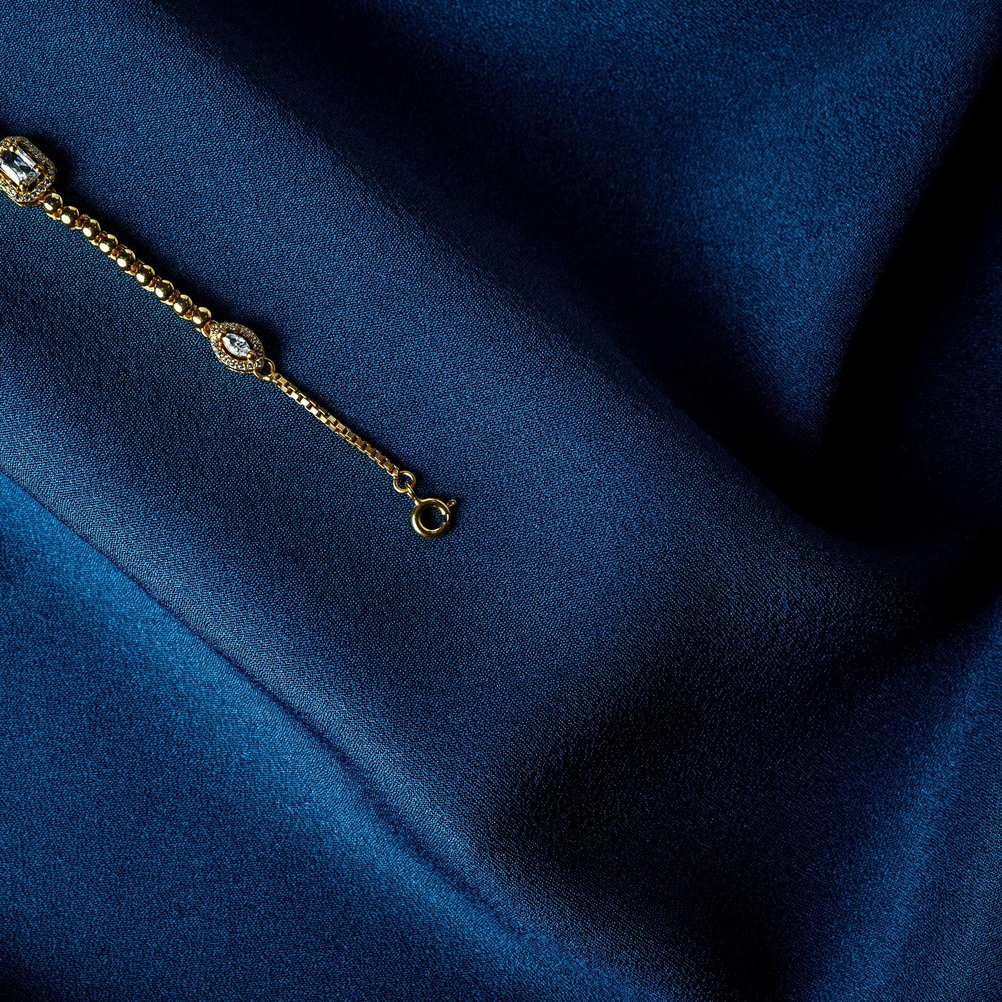 Gold ball bead chain running between the CZ stations on a 925 silver bracelet