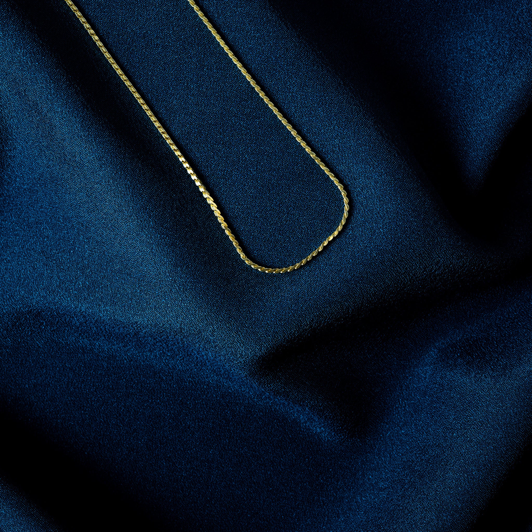 Macro of a faceted gold rope chain showing the helical twist and its facets