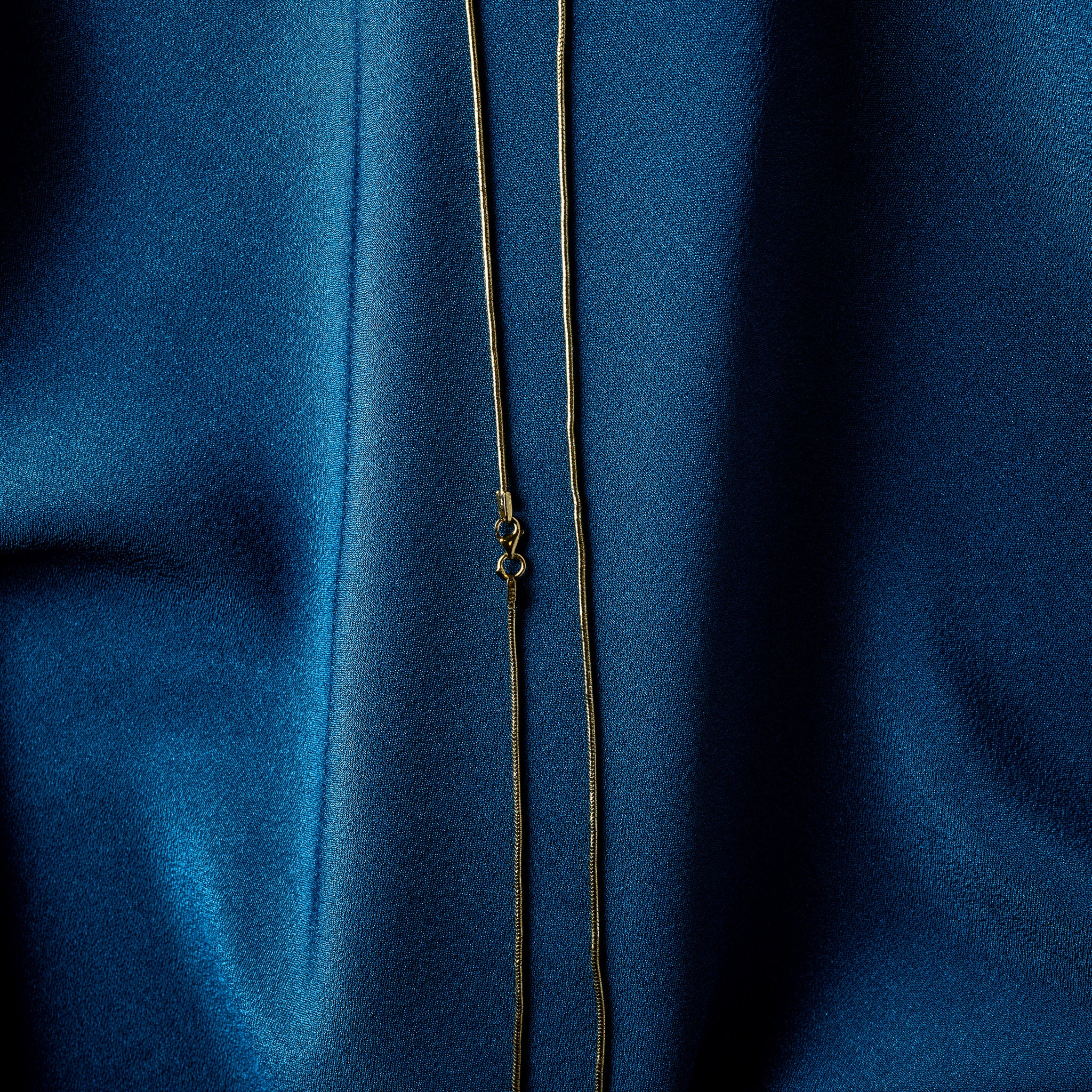 Macro of a gold snake chain showing tight transverse banding where it bends