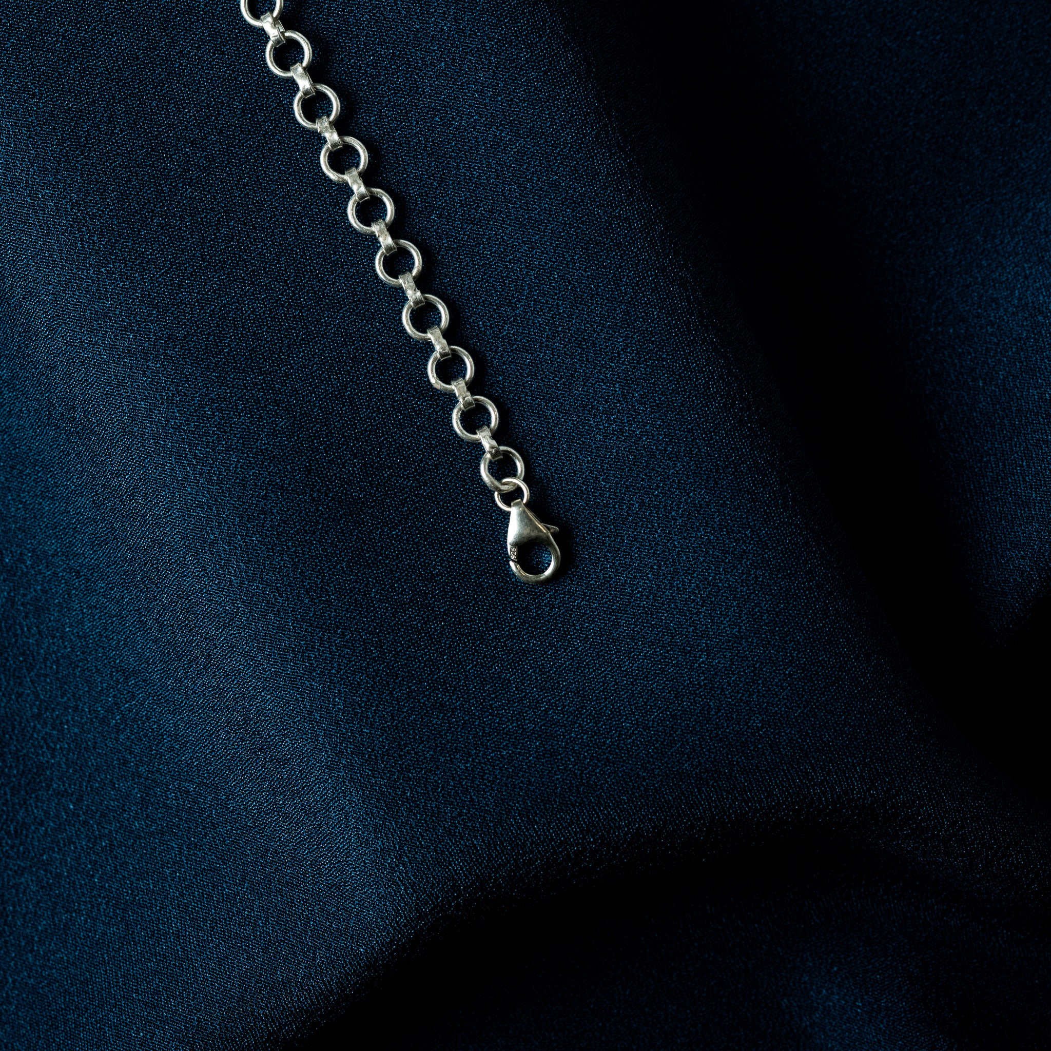 Macro of a lobster clasp on a plain silver round link back chain