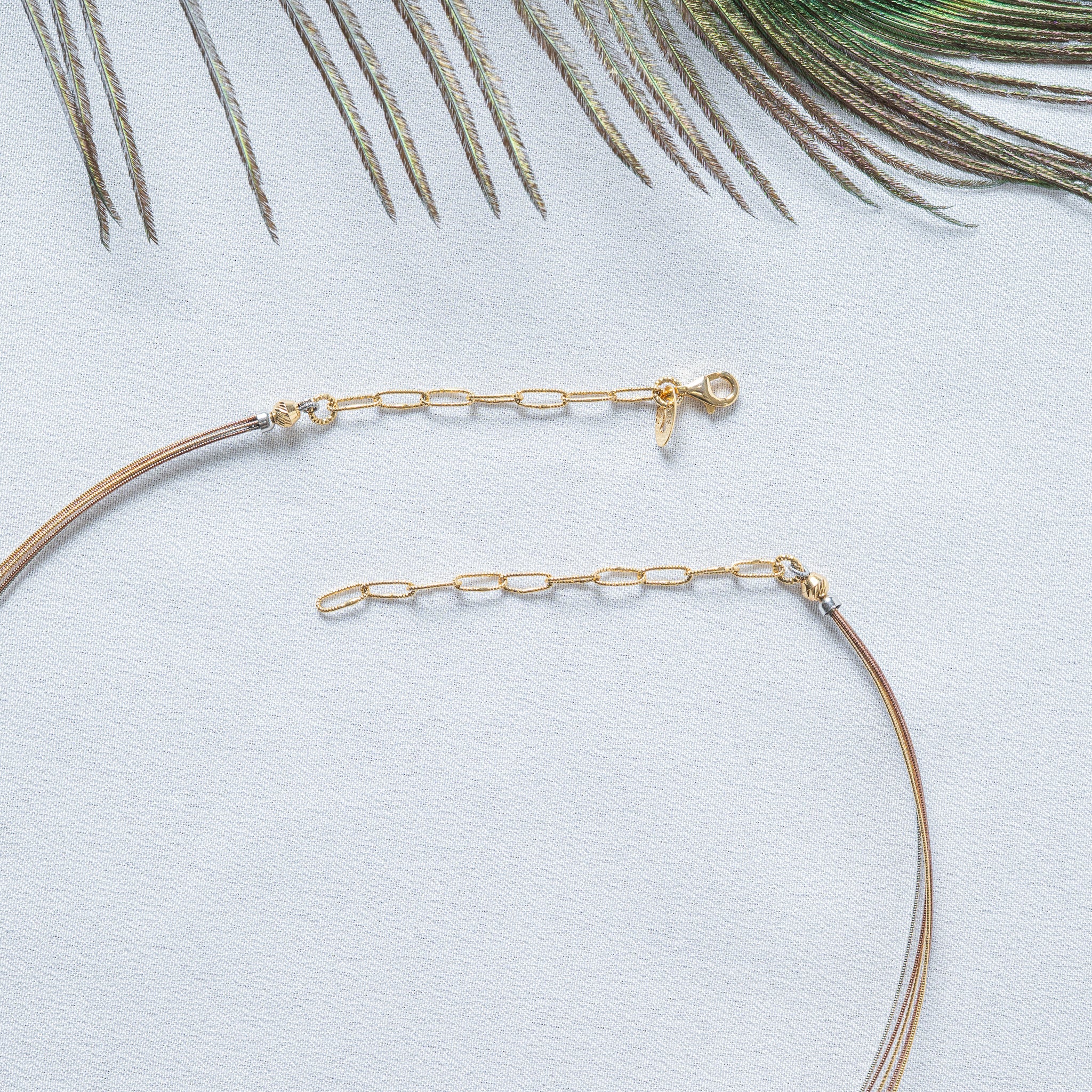 Collar opened flat showing barrel end caps, lobster clasp with leaf tag and paperclip extender