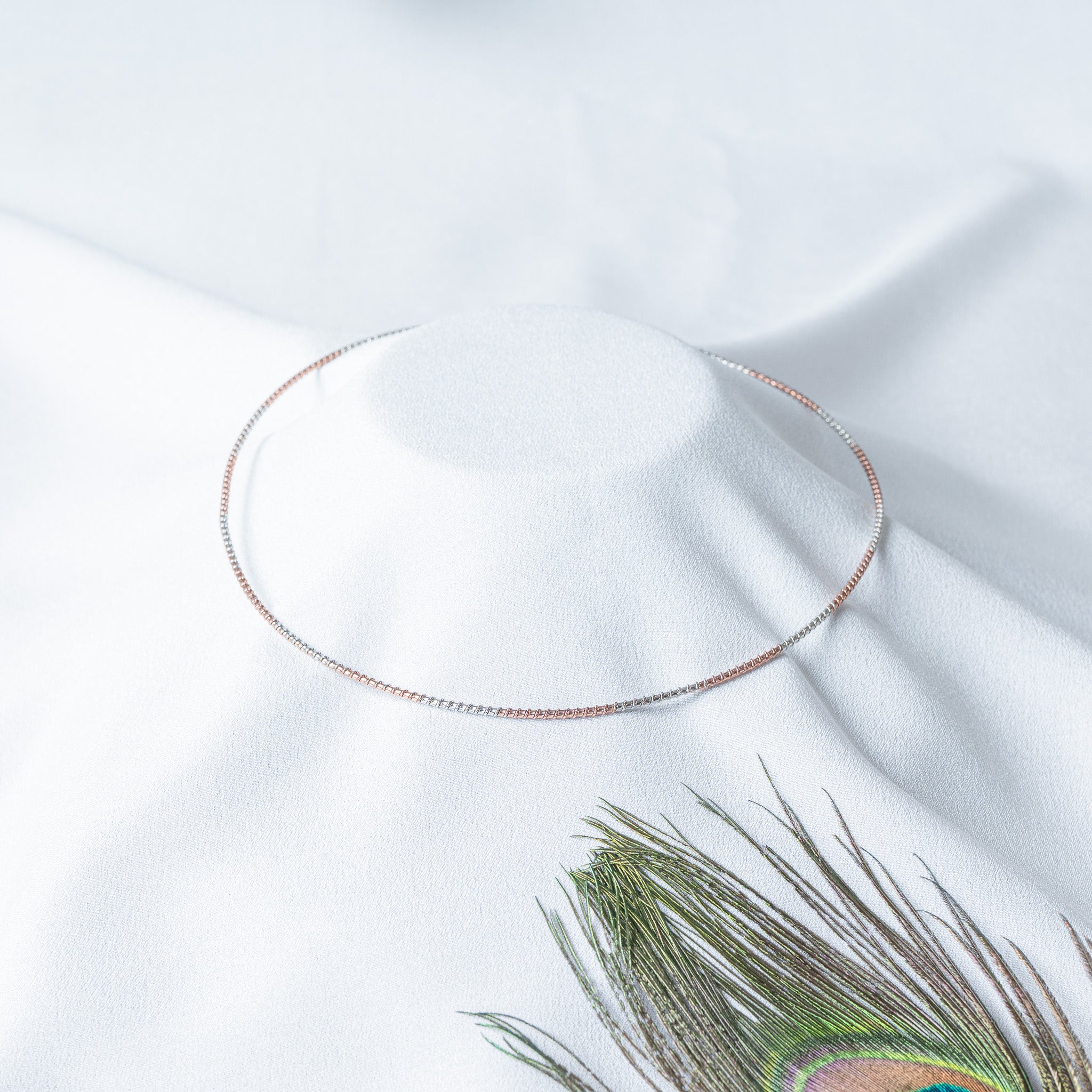 Angled view of the two tone hasli showing the rose gold and white banding along the box link