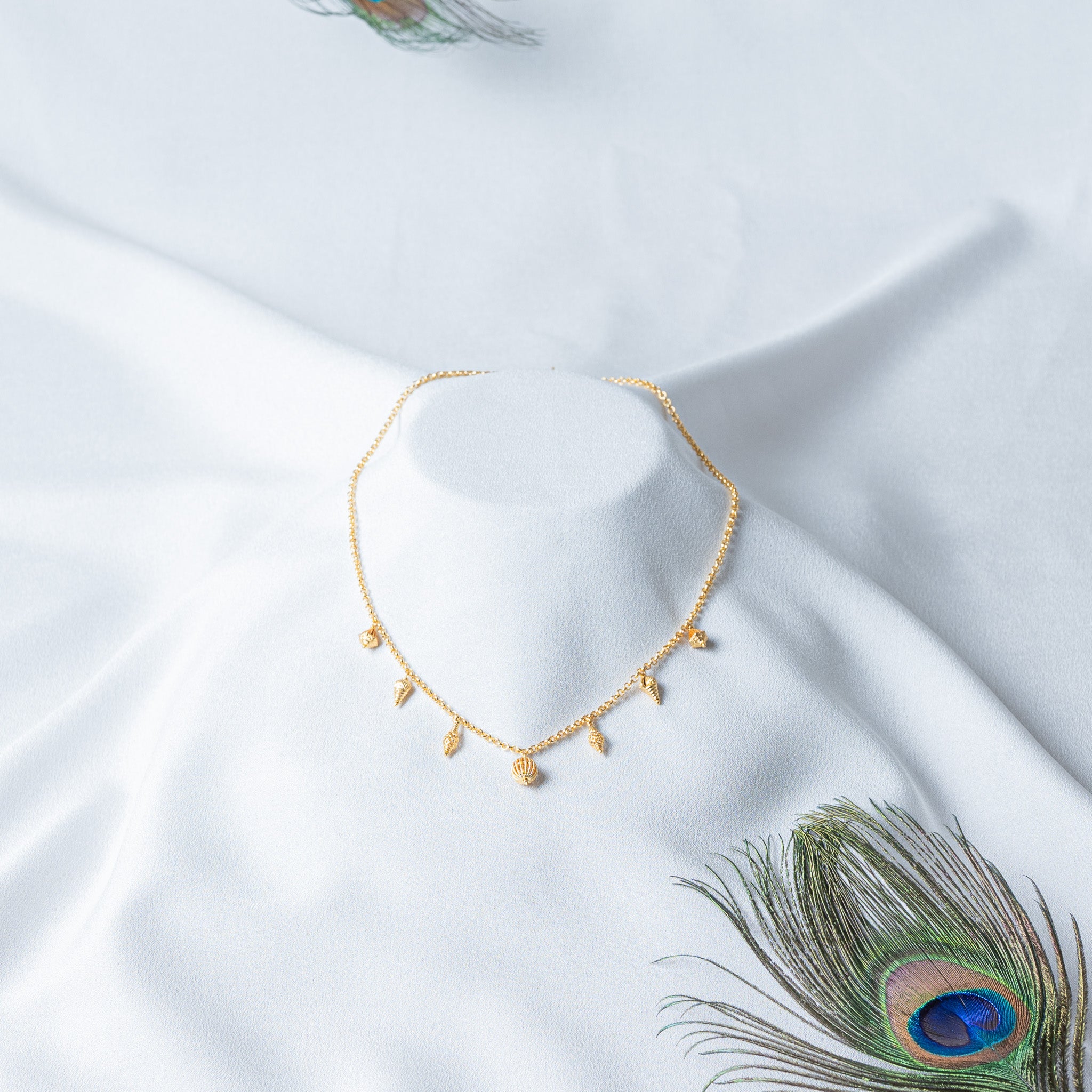 Gold charm neckchain shown from the front, the fan shell charms sitting at the outer ends