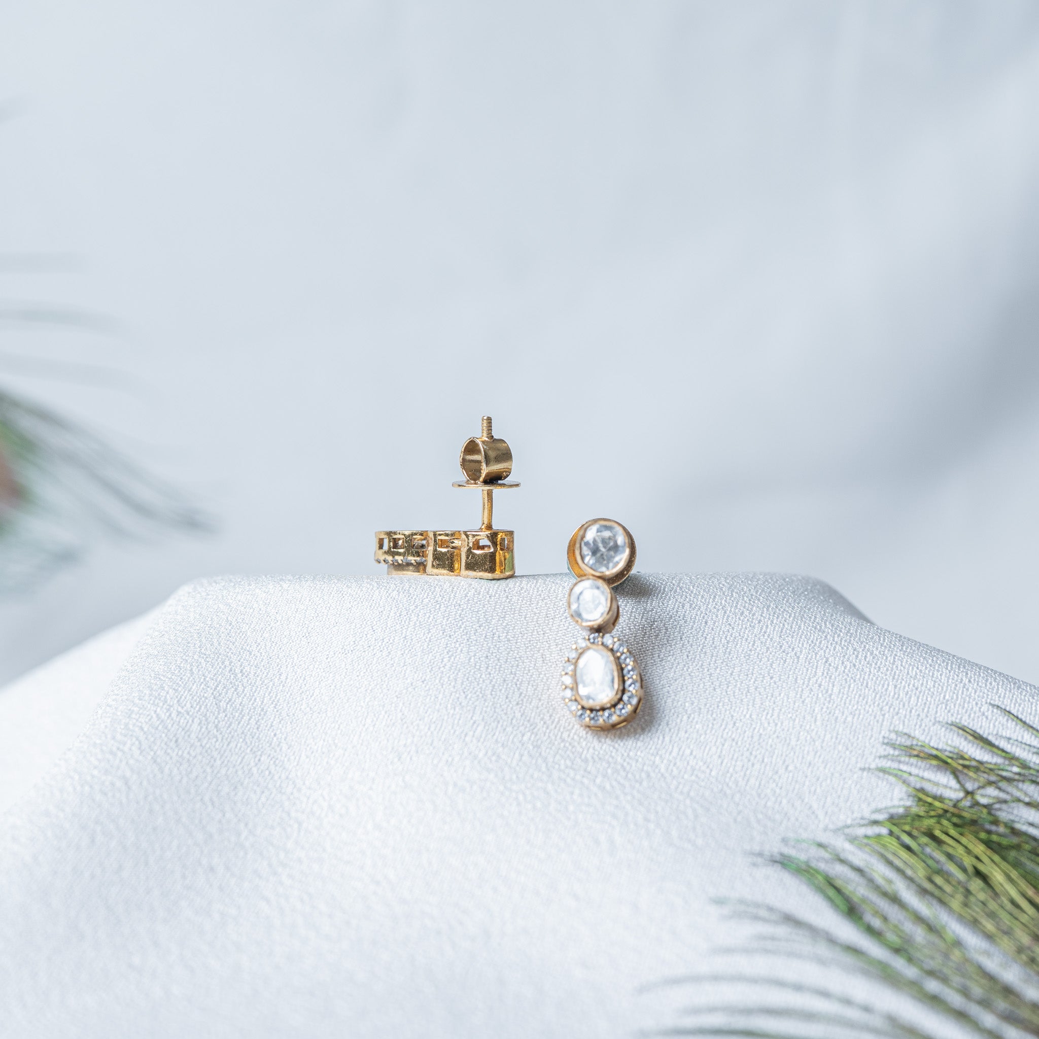 South Indian screw back post and its flat brimmed barrel nut lying beside the earring