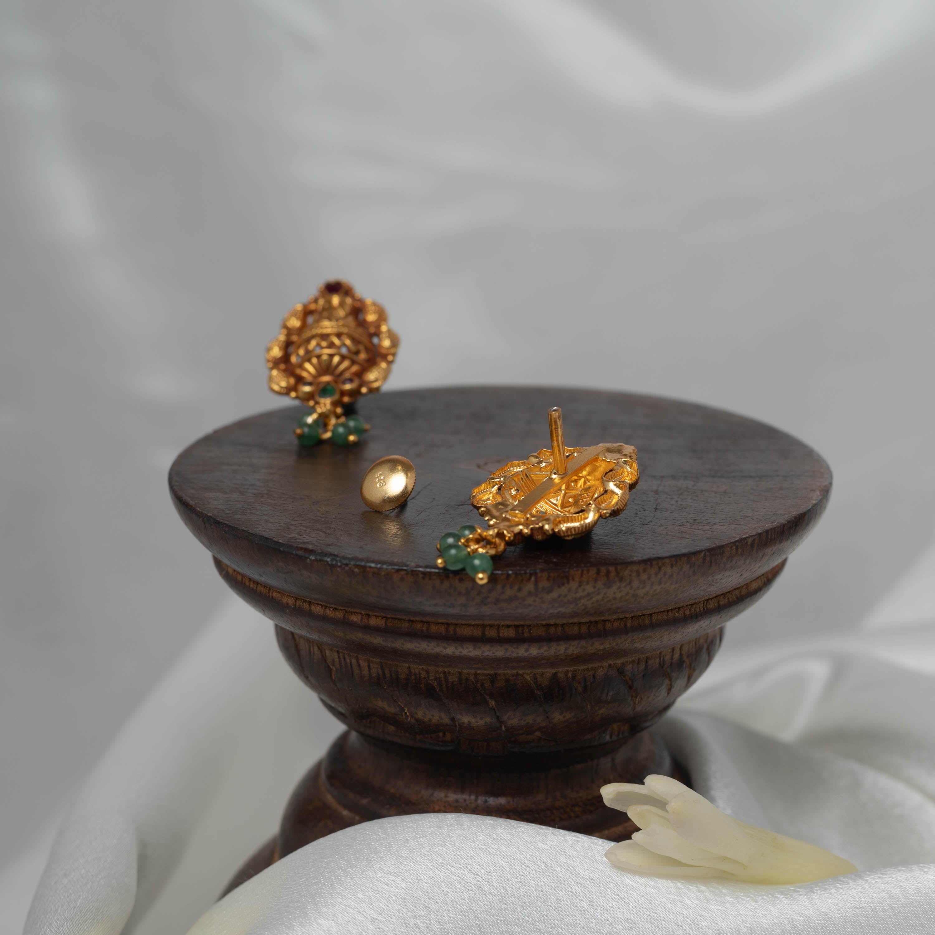 Close view of the green stones at the base of the antique gold kalash stud