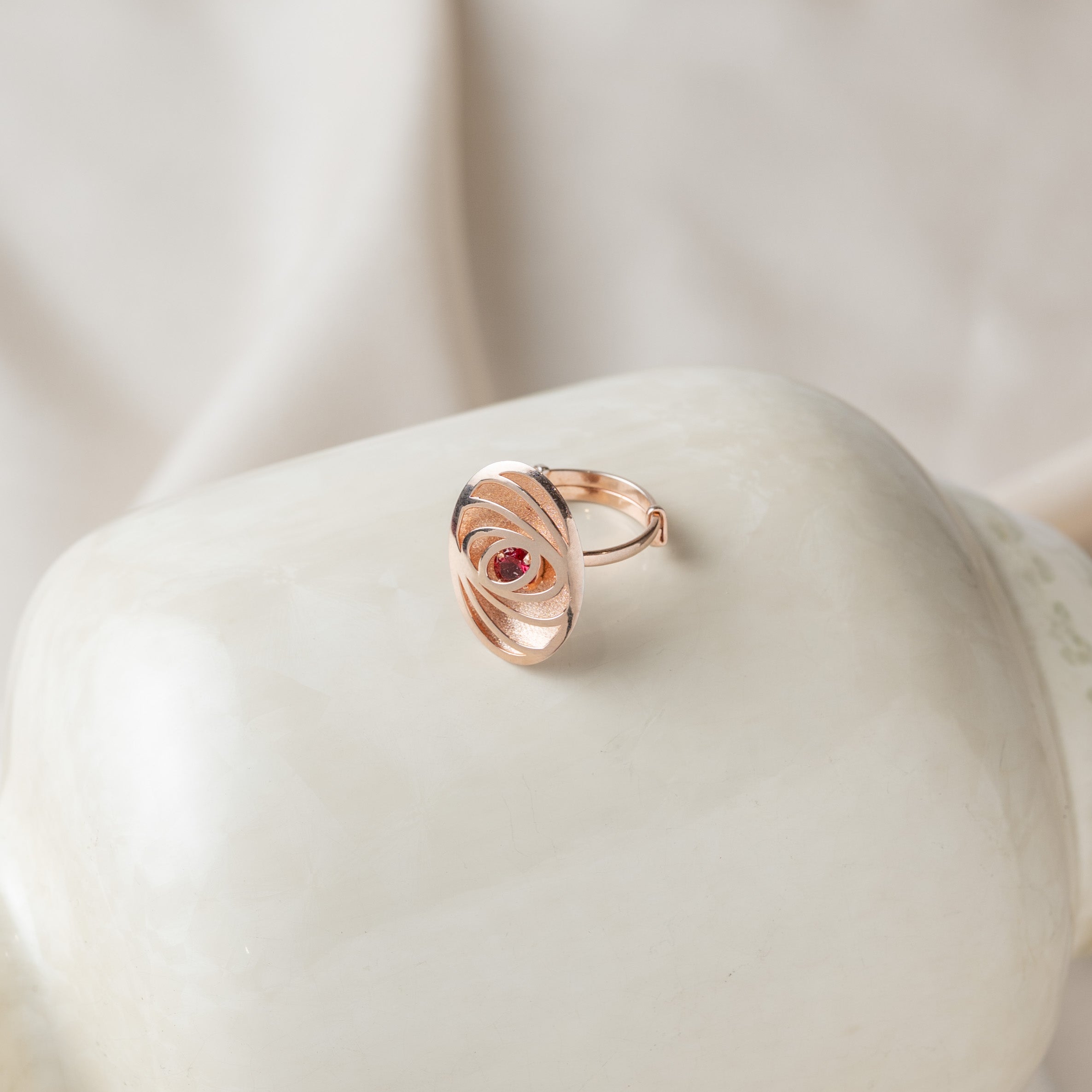 Spiral carved oval ring with a single round ruby at the centre in rose gold plated 925 silver