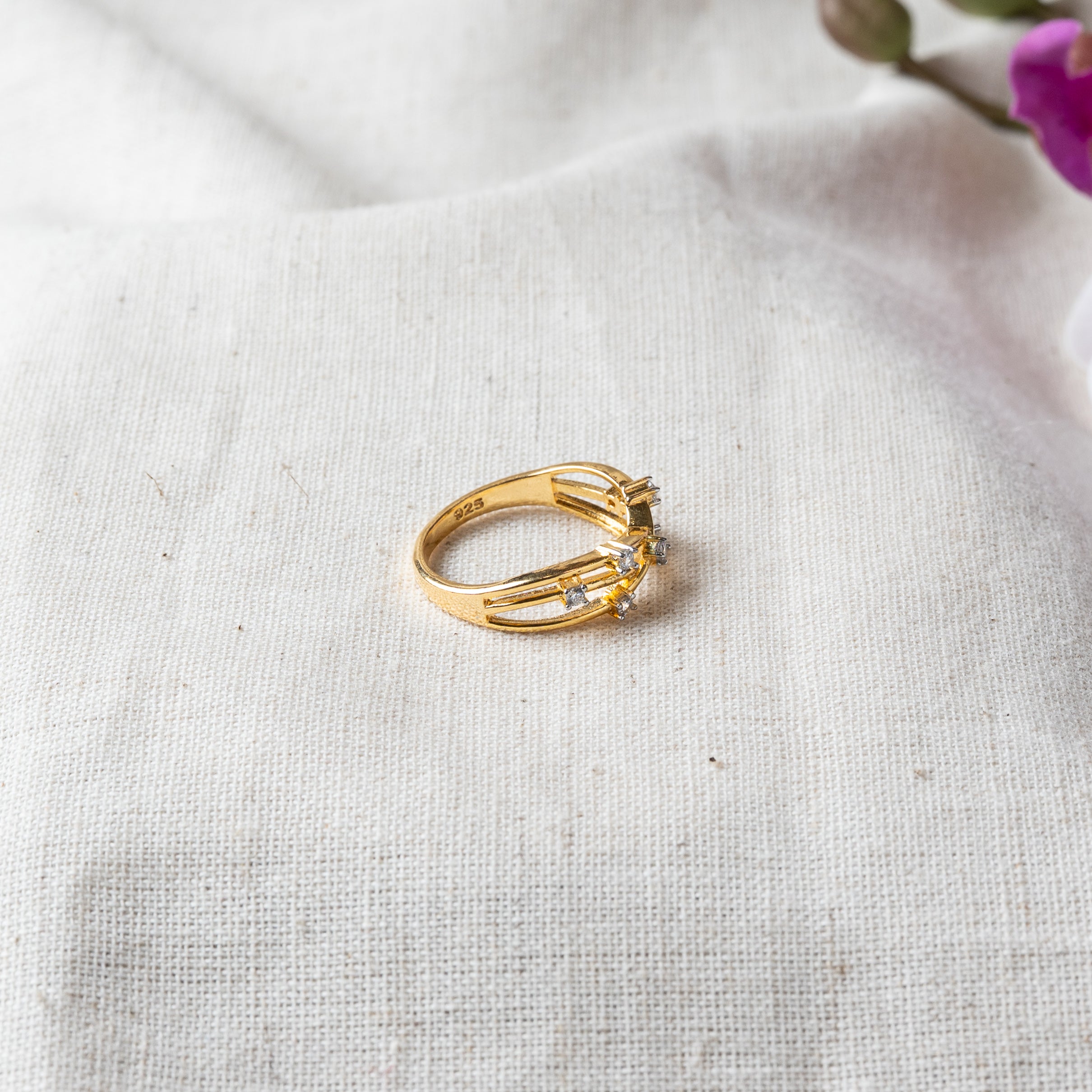 Close view of the crossing strands and CZ with the 925 stamp on the gold plated band