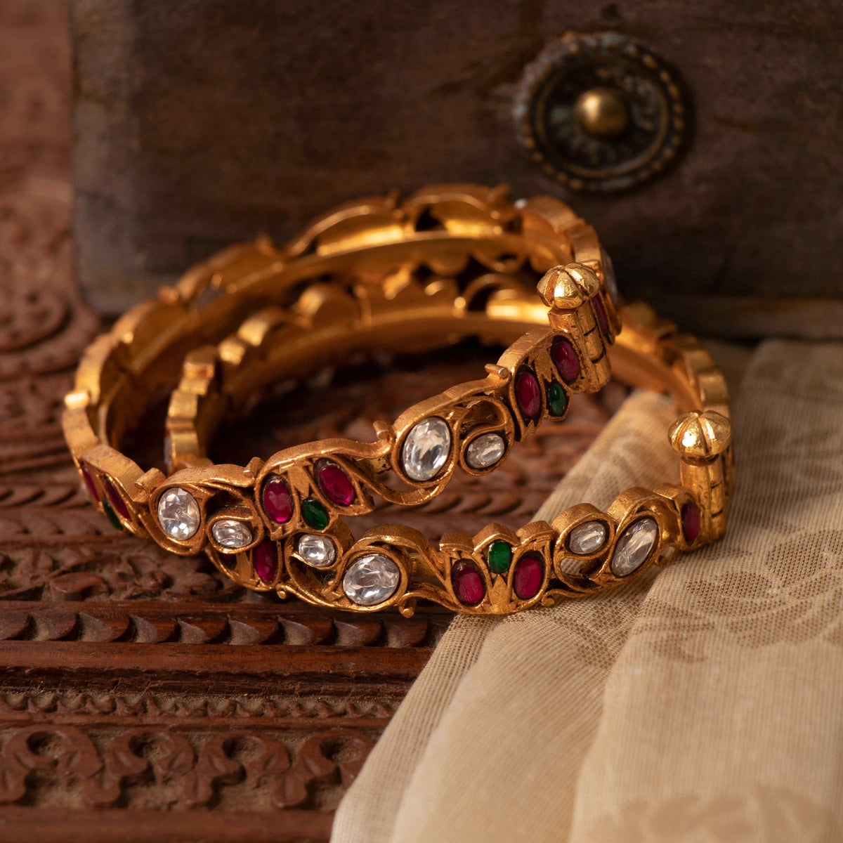 Floral vine pattern running unbroken around the bangle with white kundan ovals, angled view