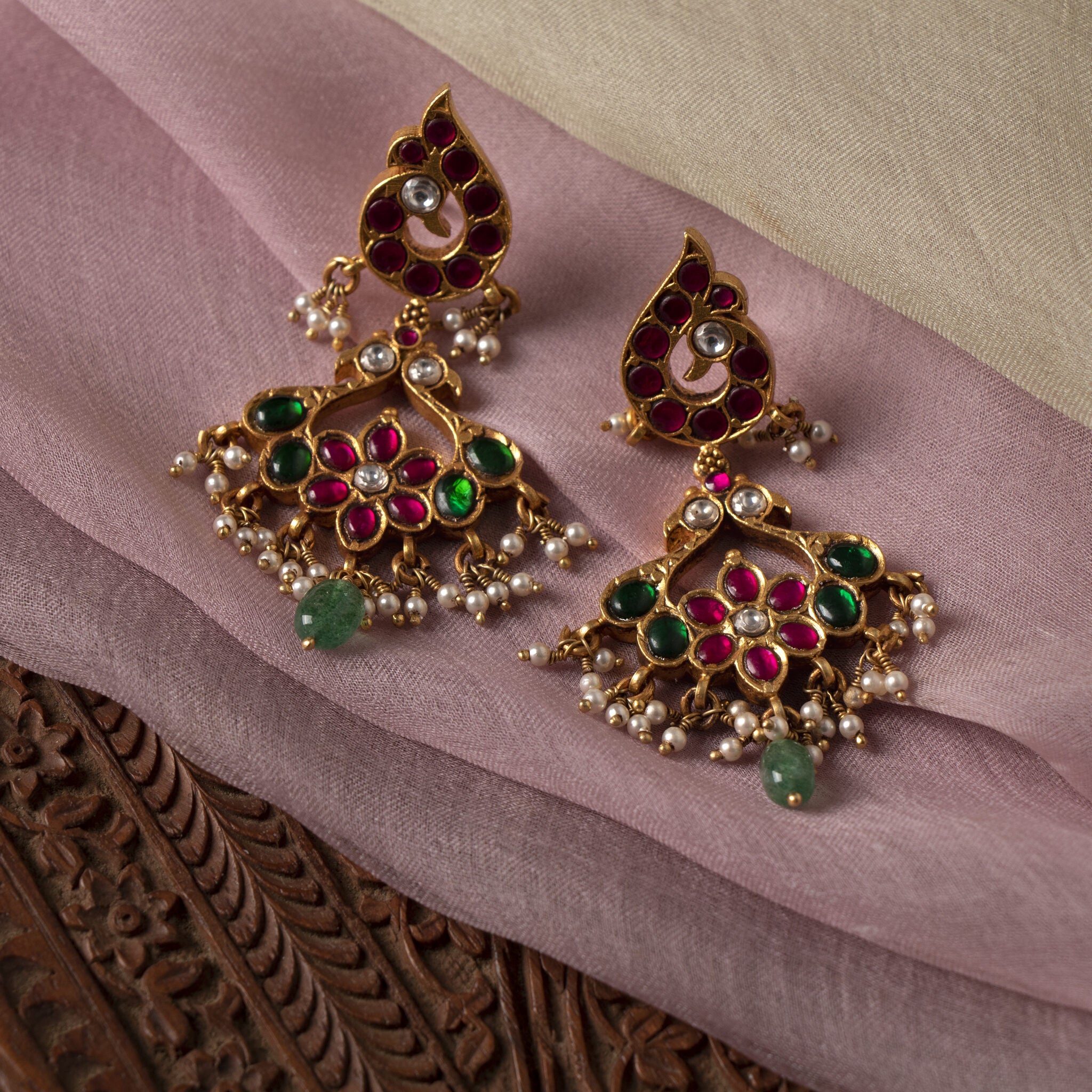 Close view of the red kundan flower with white kundan centre and a single green bead drop