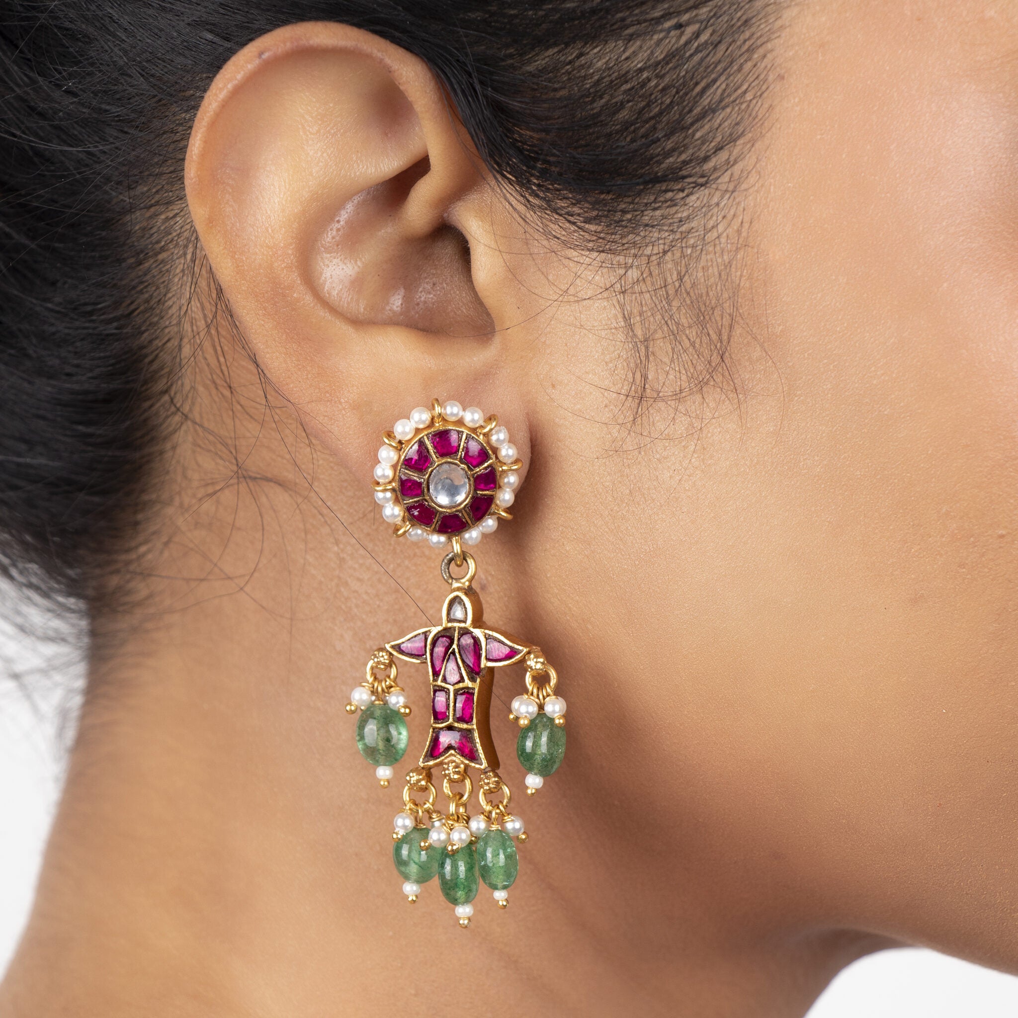 Red kundan petal stud worn on the ear, the fish and its green bead tassels dropping below