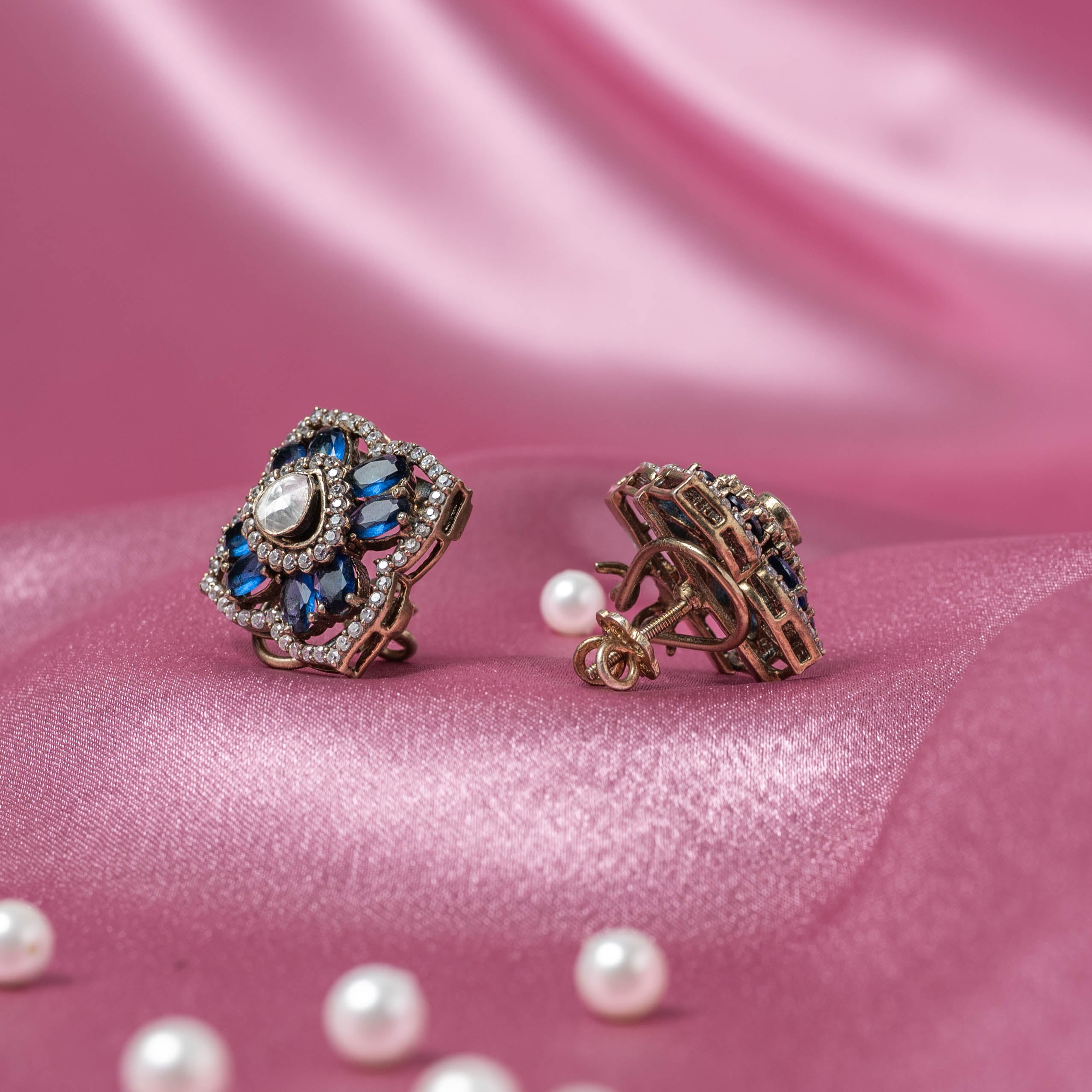 Close-up of Ishya Victorian studs handcrafted in 925 silver featuring blue sapphire petals, Moissanite Polki center and sparkling CZ stones