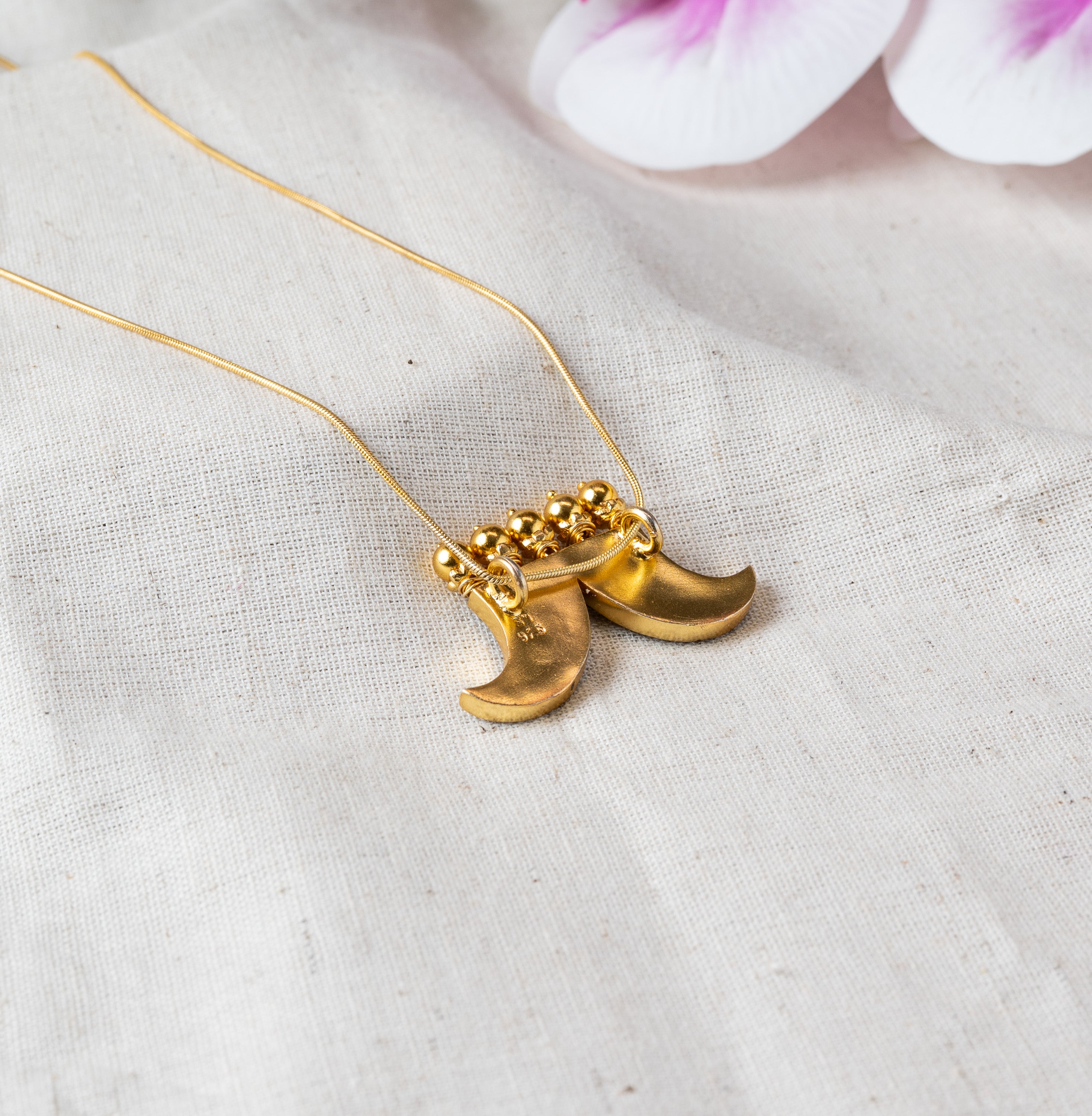 Back view of the two crescent charms showing the plain reverse and bead cluster, gold plated silver