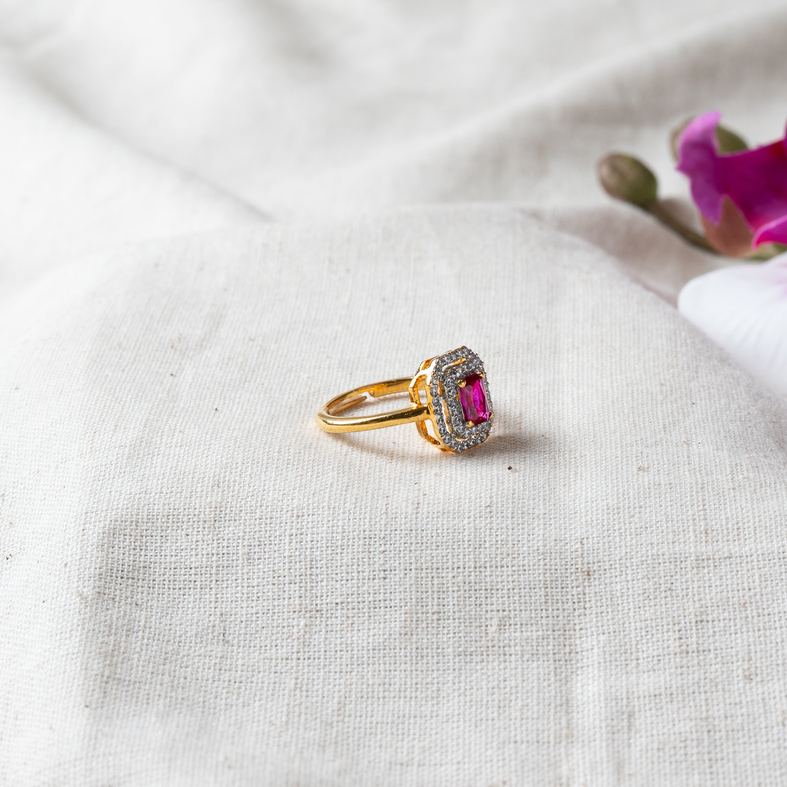 Angled close view of the rectangular ruby and CZ halo crown on the gold plated ring