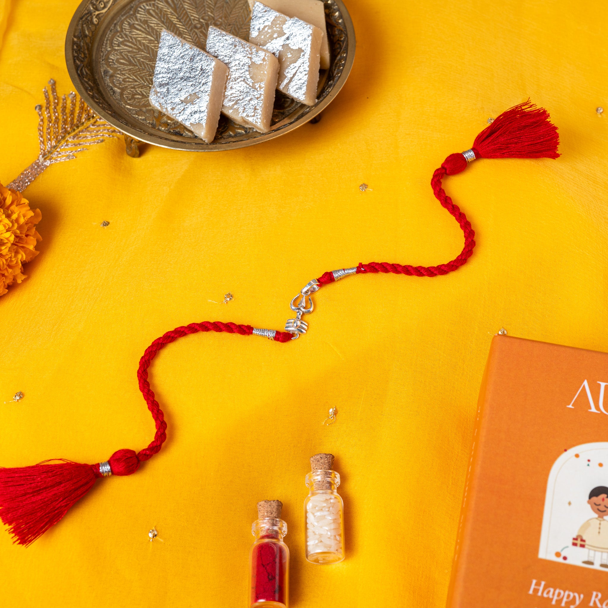 Trishul over a domed shivling in 925 silver on a red twisted silk rakhi cord with tassels
