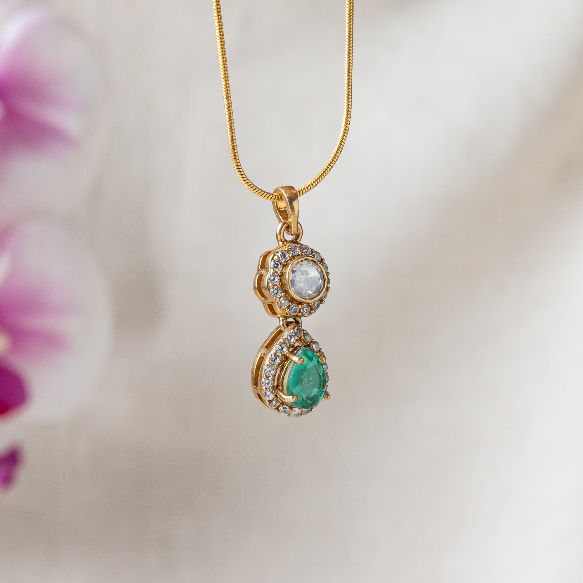 Close crop of the pendant, round polki above a pear cut emerald in a CZ frame, gold plated silver