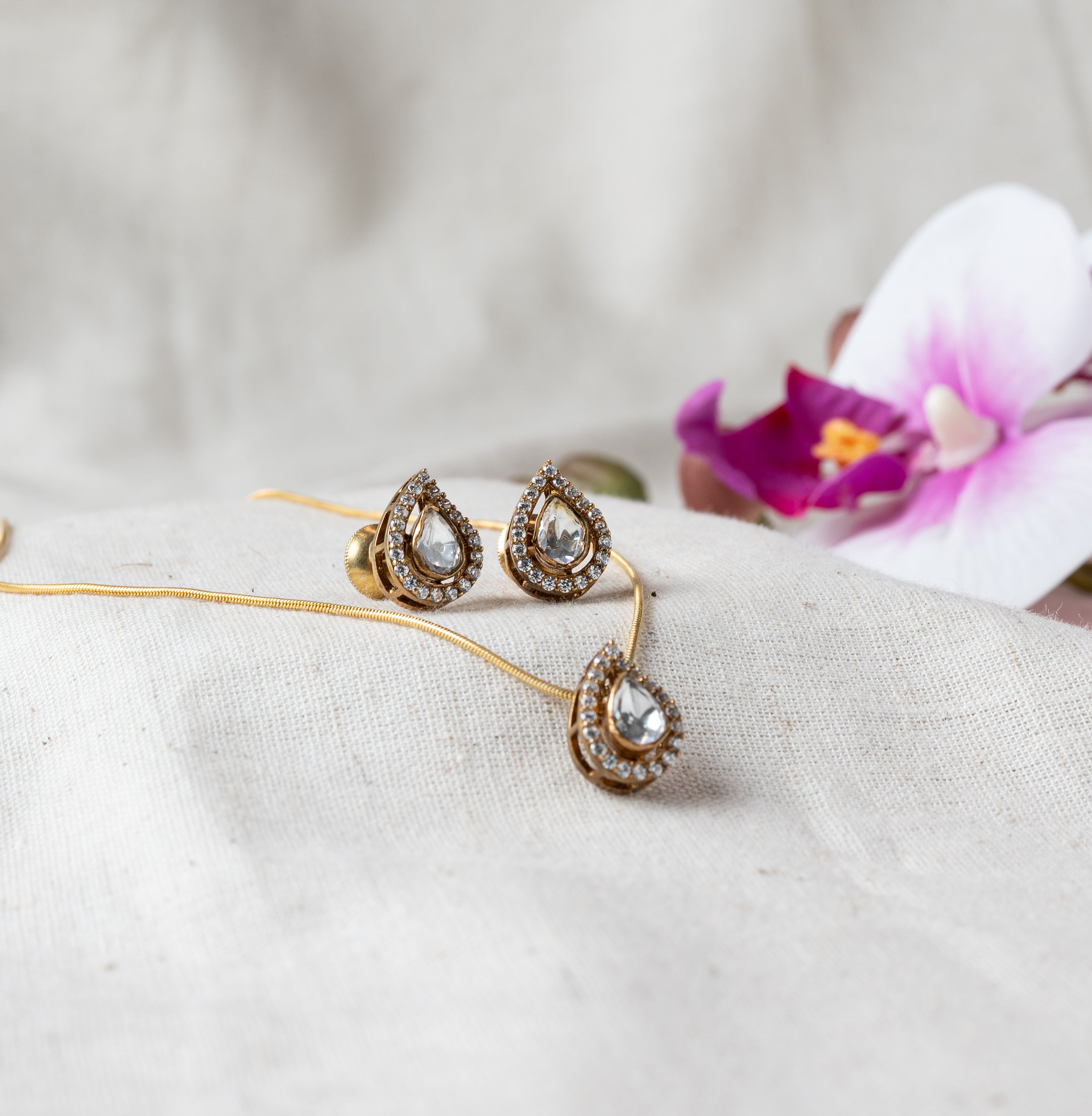 Angled view of the teardrop pendant on its chain with the stud pair beside it, Victorian plated 925 silver