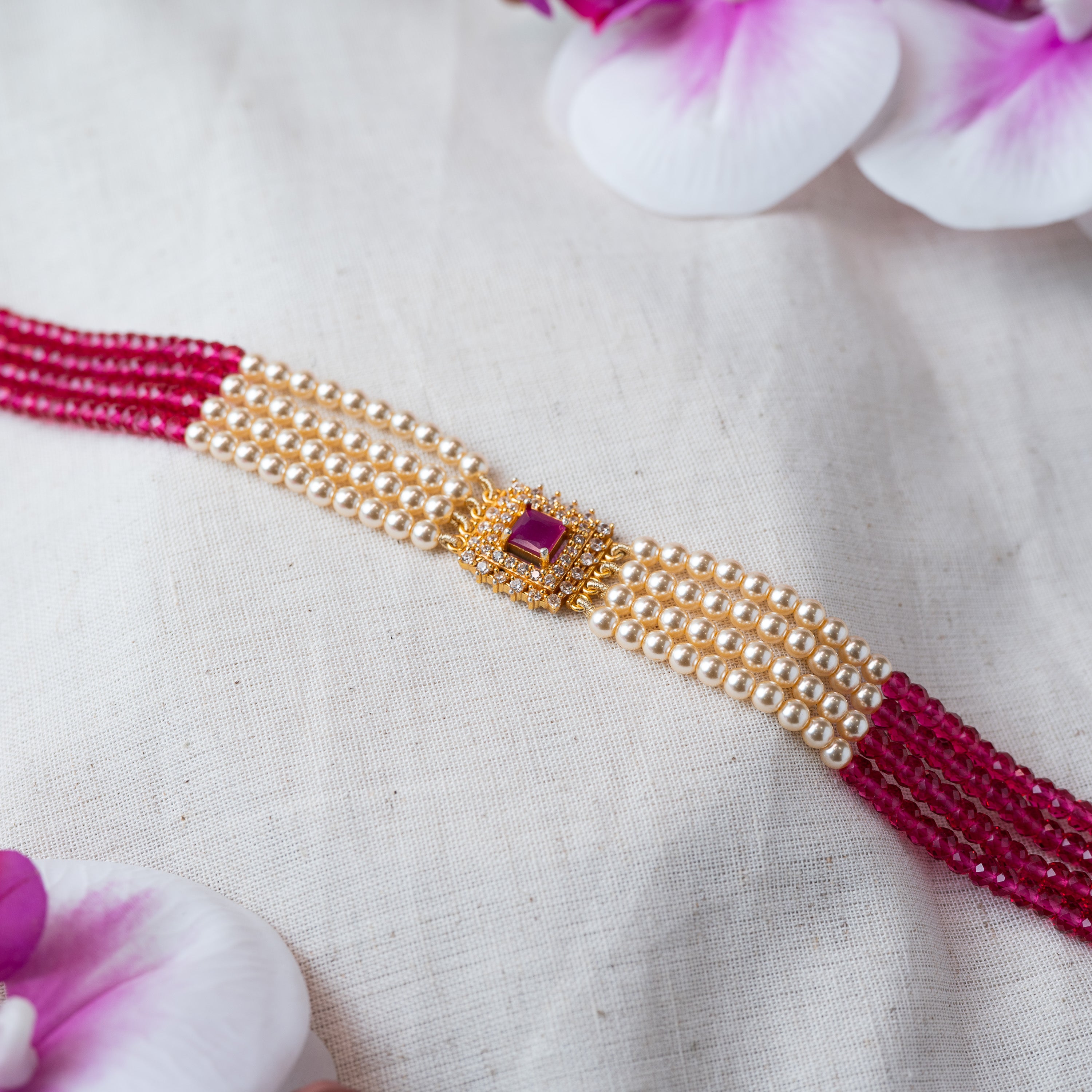 Close view of the square ruby centre framed in CZ between pearl and ruby bead strands