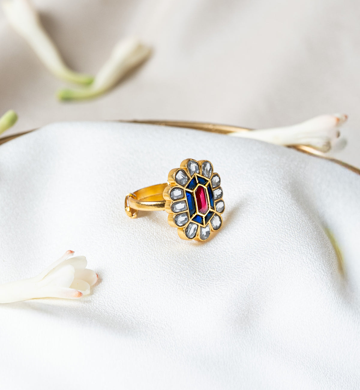 Front view of the kundan flower ring showing six flat cut blue kundan around the centre stone