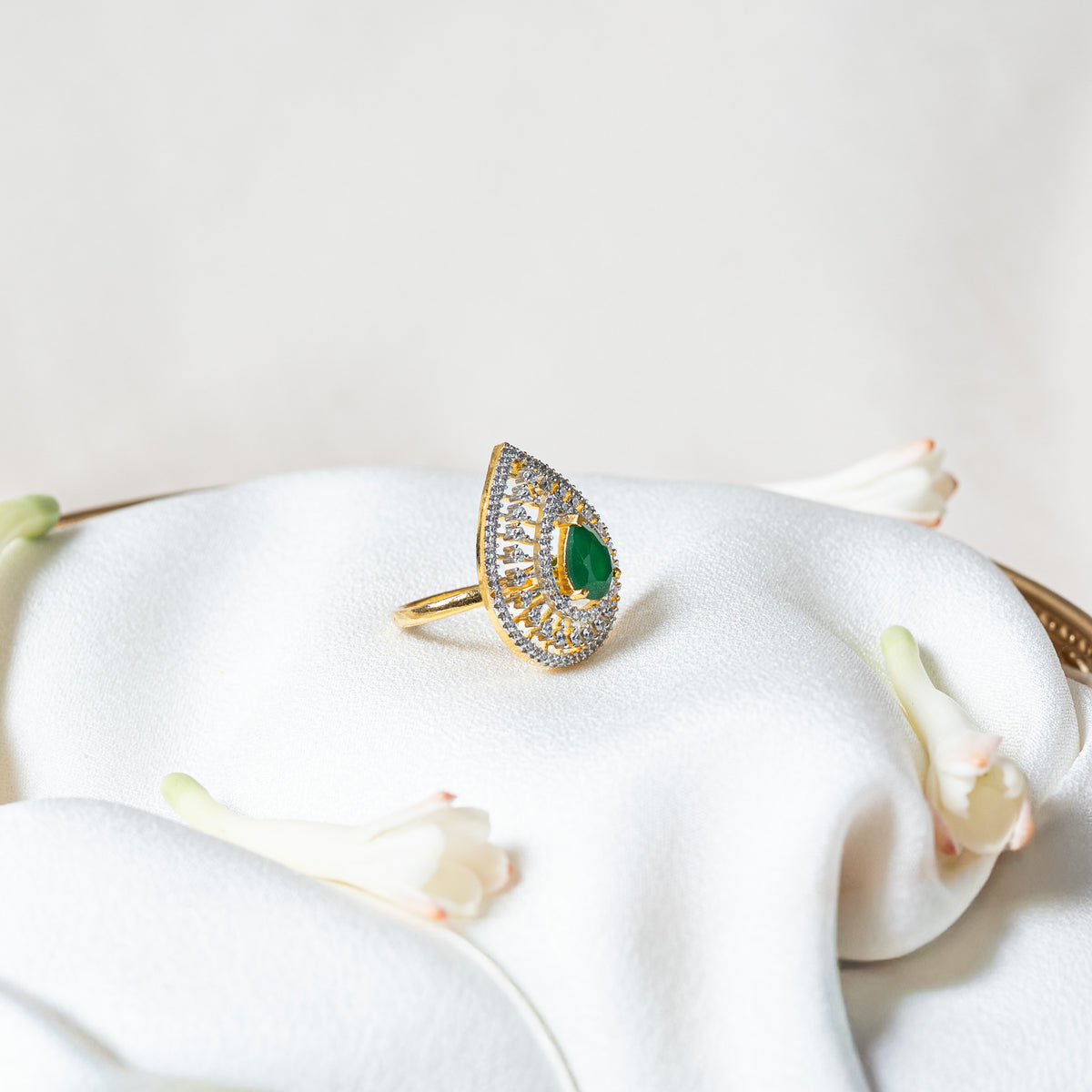 Side view of the green teardrop ring showing the prong set centre stone standing above the rows of CZ