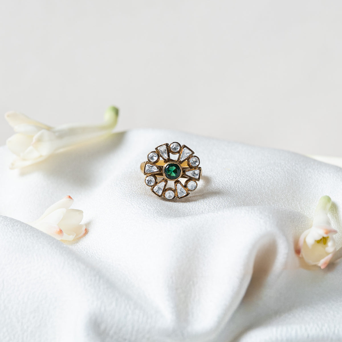 Victorian rosette ring with a round green stone ringed by twelve uncut white stones in dark rims